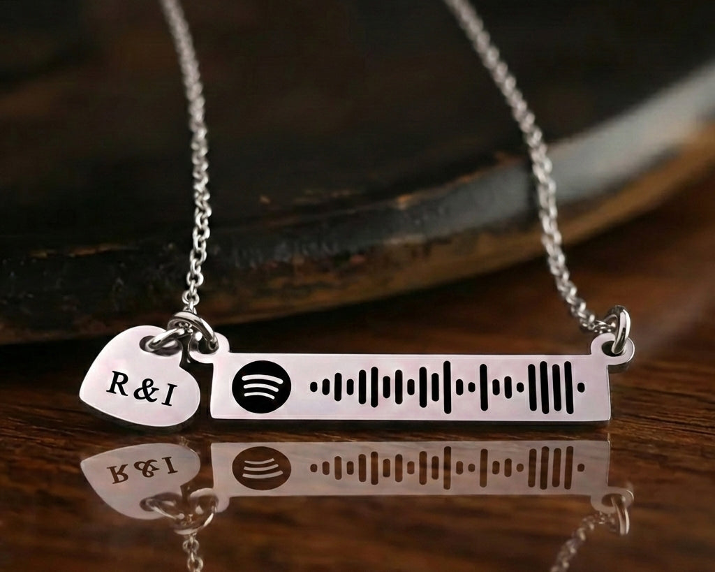 Personalized music bar necklace with engraved song code and heart charm displayed on a dark background, Belle Fever