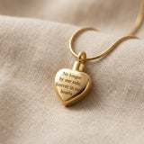 Always Love cremation necklace with gold heart urn pendant on delicate chain displayed on soft neutral fabric