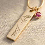 Close up of birthflower personalised necklace with engraved bar and birthstone charm detail