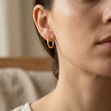 Woman wearing chic sleeper hoop earrings with small round hoop design