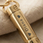 Close up of cylinder cremation necklace showing engraved detail on urn pendant