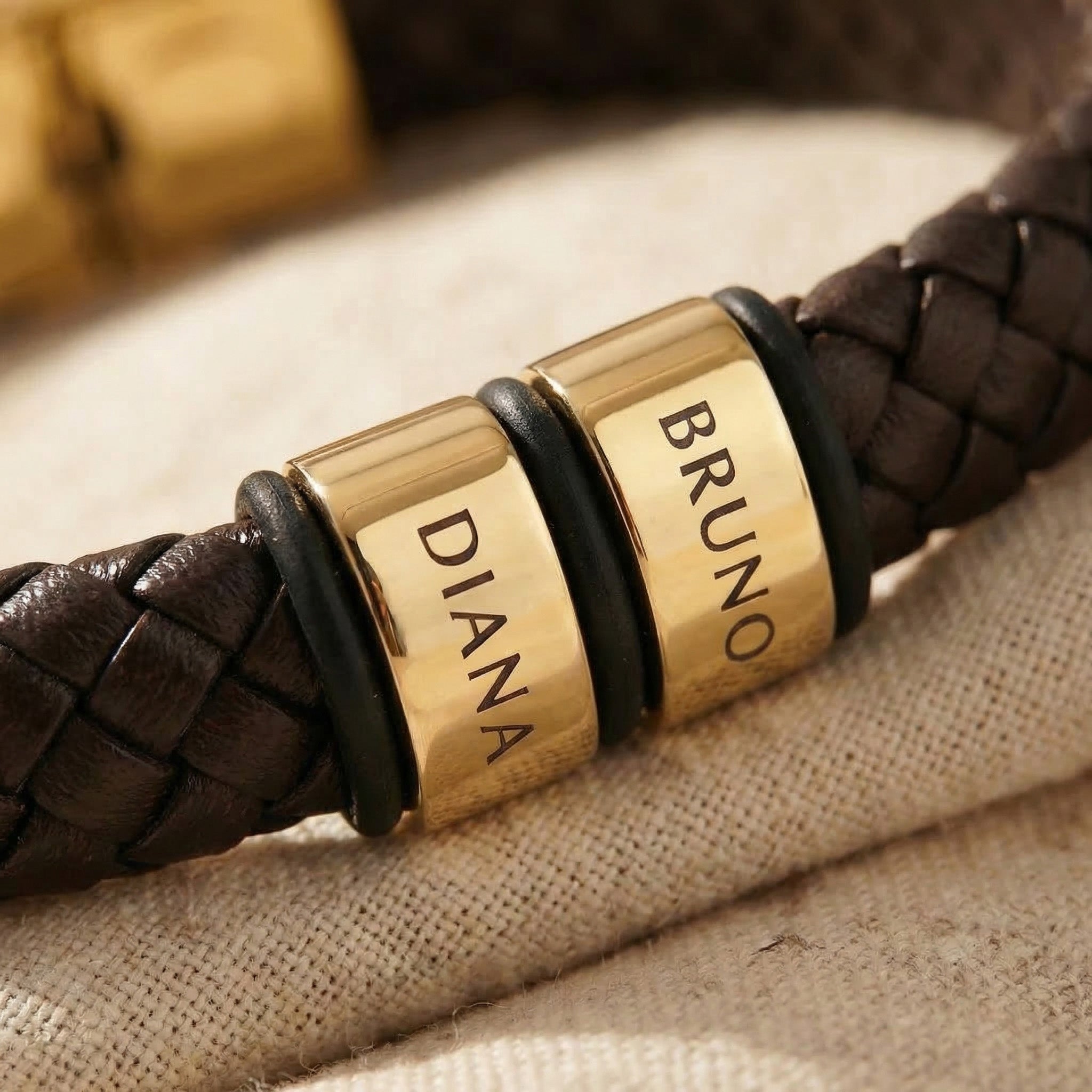 Close-up of personalised leather bracelet with engraved name charms and braided leather detail